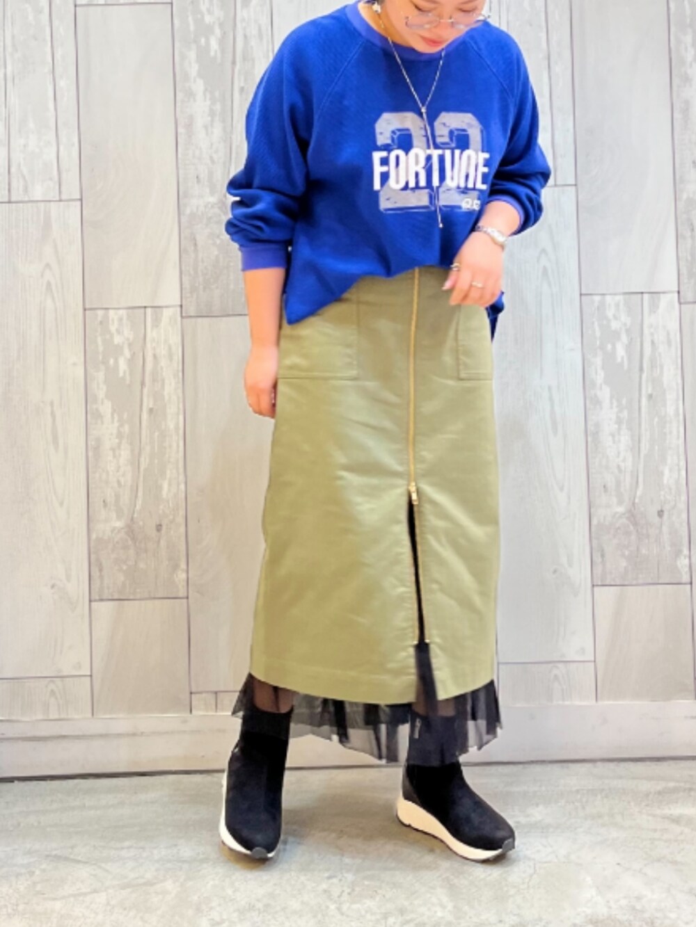 グリーン系のスカート、ブルー系のTシャツ/カットソー、ブラック系のブーツを着用したレディースの秋コーディネートの2枚目の写真