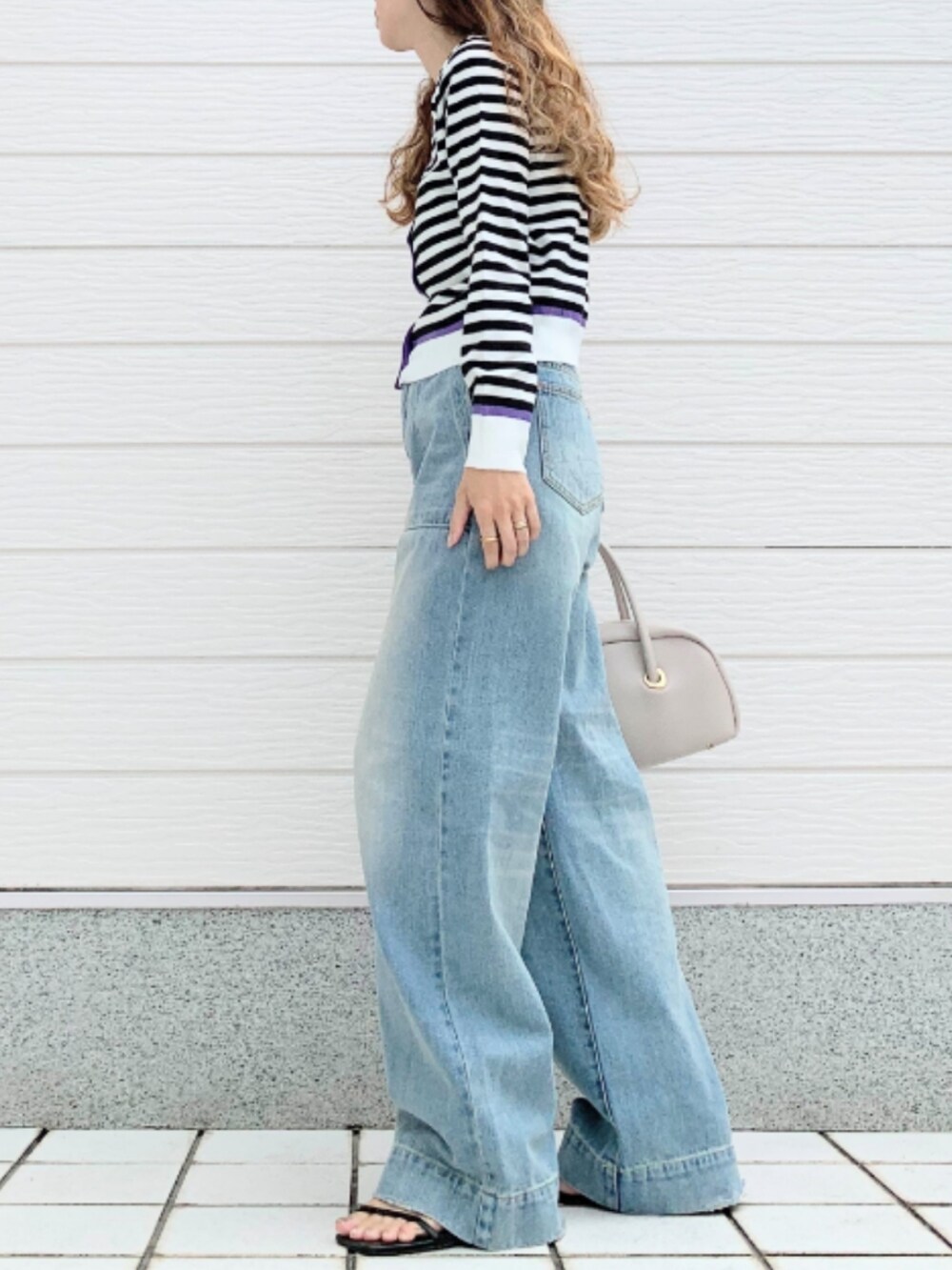 ブルー系のデニムパンツ、ホワイト系のボストンバッグ、ホワイト系のカーディガン/ボレロを着用したレディースの夏コーディネートの2枚目の写真