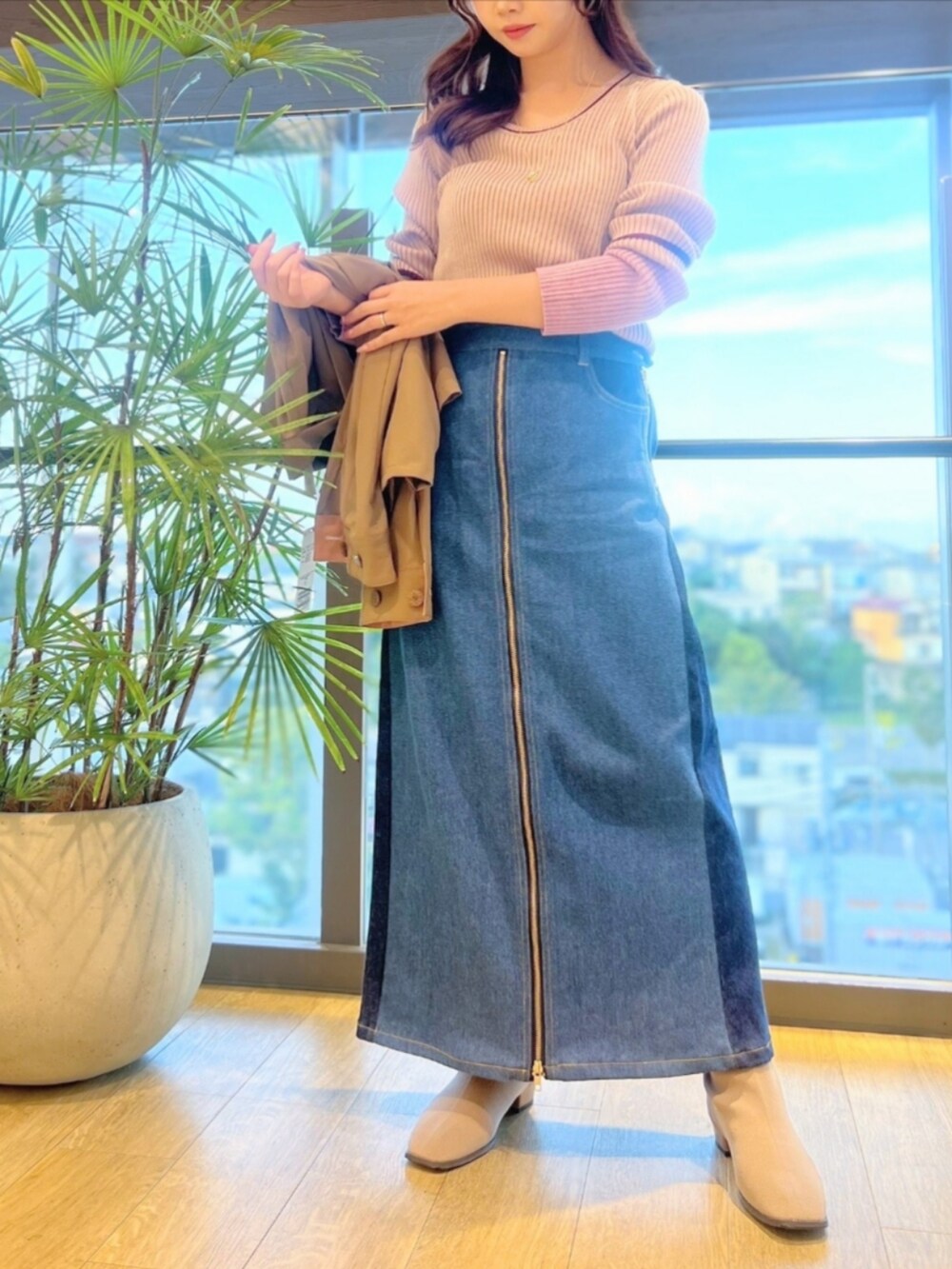 ブルー系のデニムパンツ、ベージュ系のブーツ、ピンク系のニット/セーターを着用したレディースの秋コーディネートの3枚目の写真