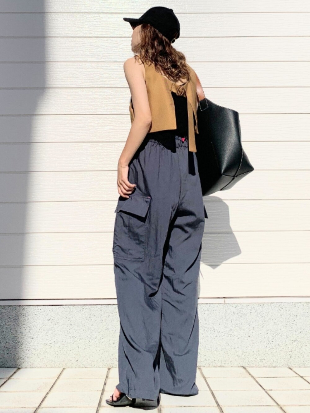 グレー系のその他パンツ、イエロー系のベスト、ブラック系のショルダーバッグを着用したレディースの夏コーディネートの3枚目の写真