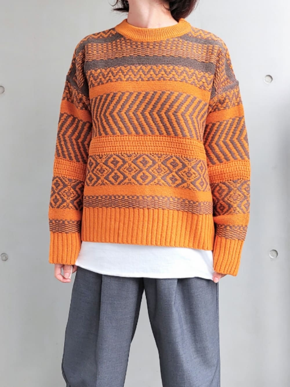 グレー系のスラックス、ホワイト系のTシャツ/カットソー、イエロー系のニット/セーターを着用したレディースの秋コーディネートの3枚目の写真