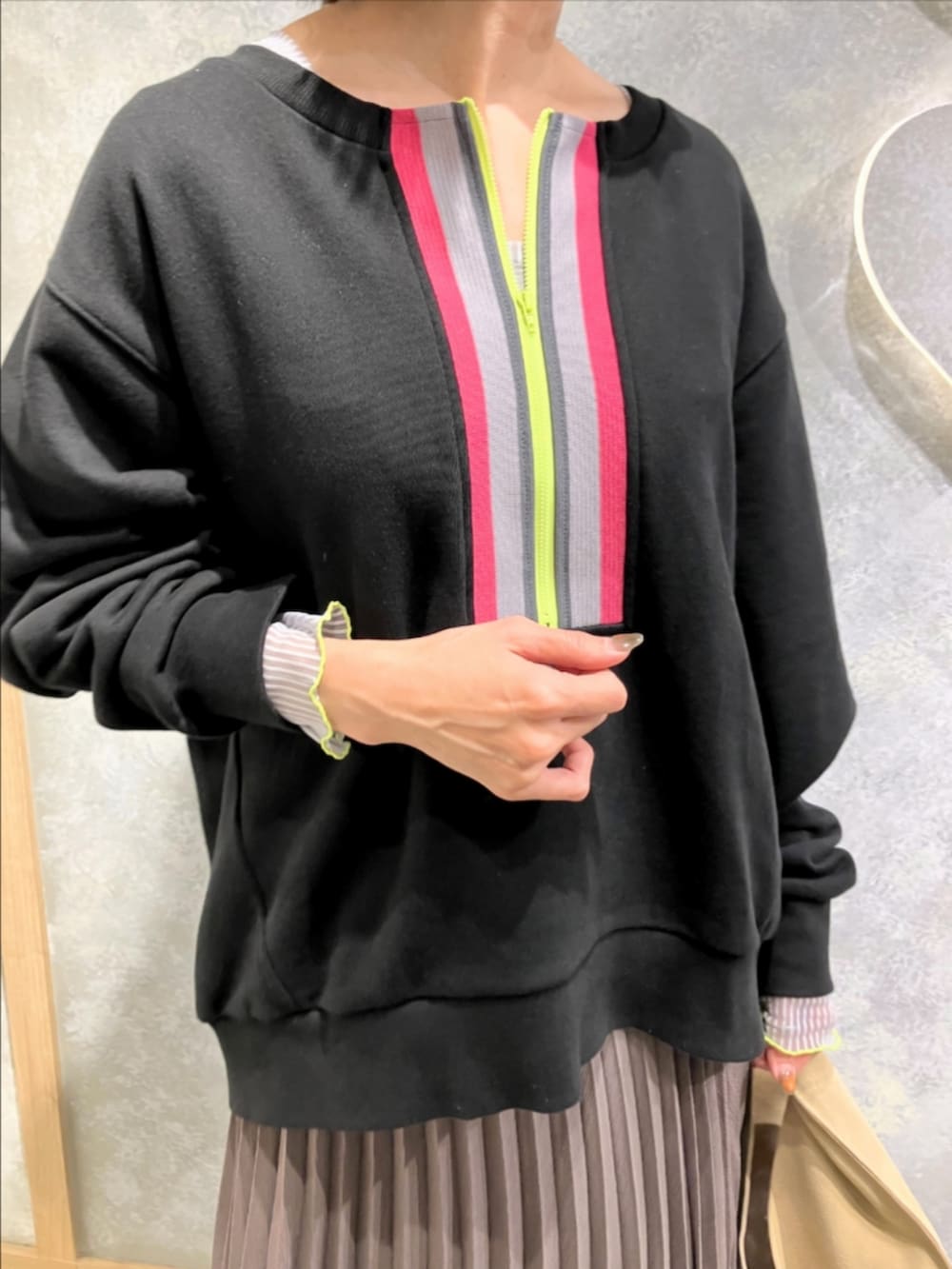 グリーン系のスカート、ベージュ系のトートバッグ、ブラック系のスウェットを着用したレディースの秋コーディネートの3枚目の写真