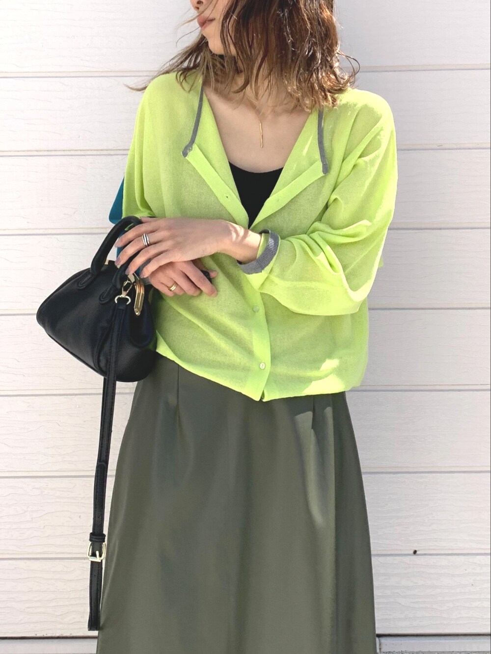 ブラック系のショルダーバッグ、グリーン系のスカート、グリーン系のカーディガン/ボレロを着用したレディースの春コーディネートの2枚目の写真