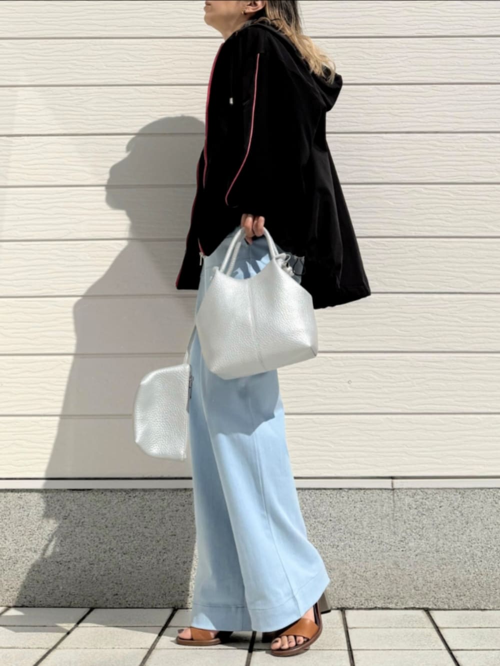 ブルー系のデニムパンツ、ブラック系のパーカー、シルバー系のトートバッグを着用したレディースの春コーディネートの2枚目の写真