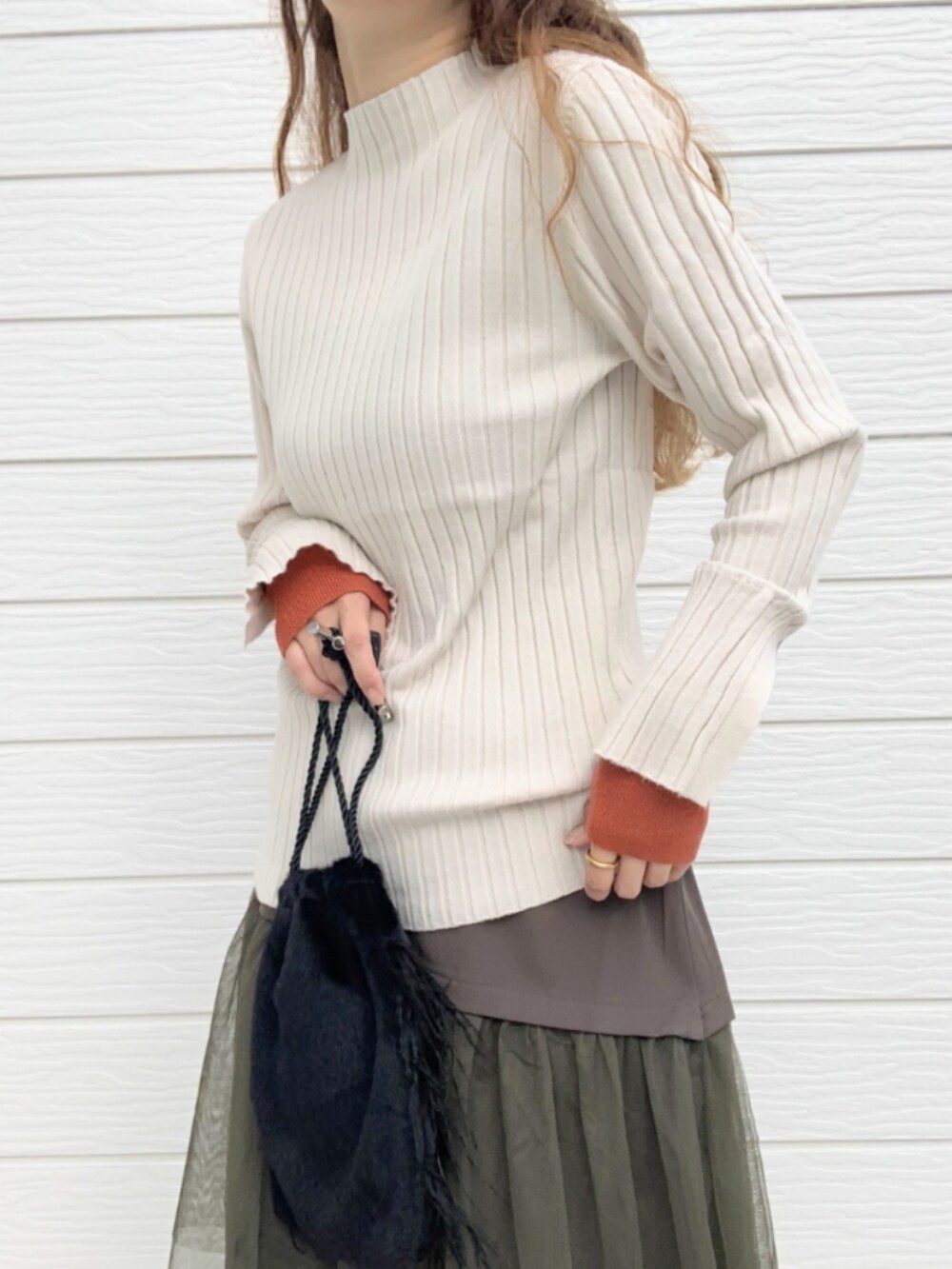 ブラウン系のブーツ、ホワイト系のニット/セーター、ブラック系のクラッチバッグを着用したレディースの秋コーディネートの5枚目の写真