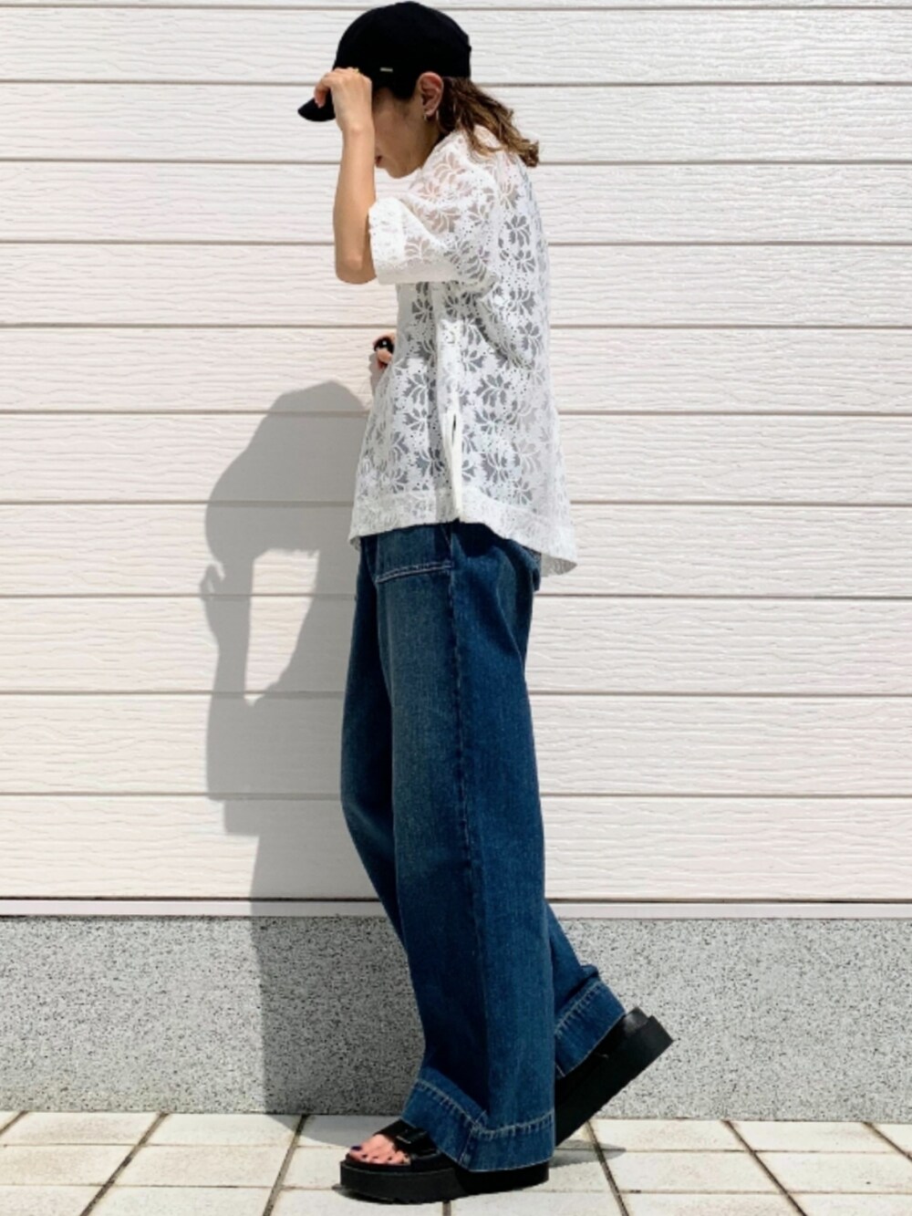 ブラック系のサンダル、ブルー系のデニムパンツ、ホワイト系のTシャツ/カットソーを着用したレディースの春コーディネートの2枚目の写真