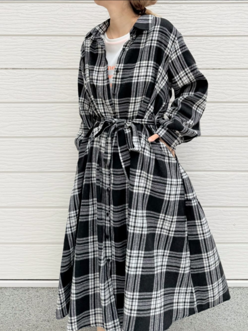 ブラック系のブーツ、ブラック系のシャツワンピース、ホワイト系のTシャツ/カットソーを着用したレディースの秋コーディネートの3枚目の写真