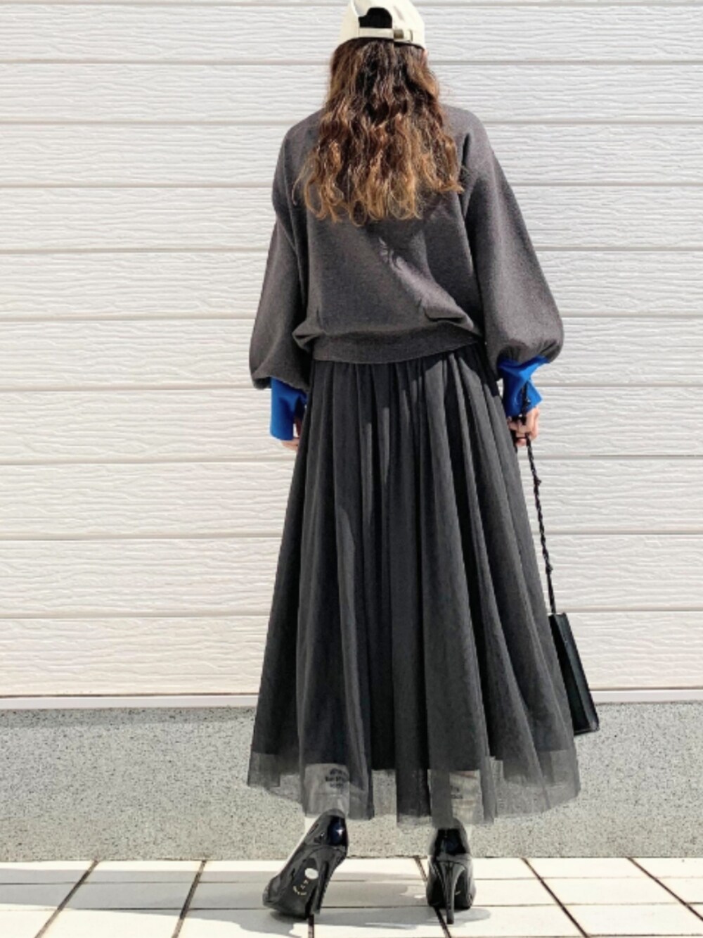 ブラック系のスカート、グレー系のニット/セーターを着用したレディースの秋コーディネートの3枚目の写真