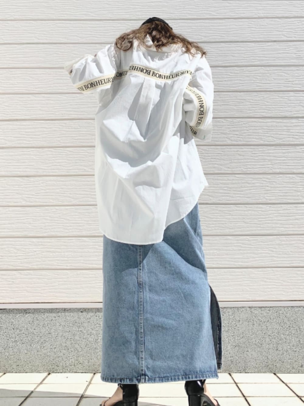 ブルー系のデニムスカート、ホワイト系のシャツ/ブラウス、ブラック系のキャップを着用したレディースの春コーディネートの2枚目の写真