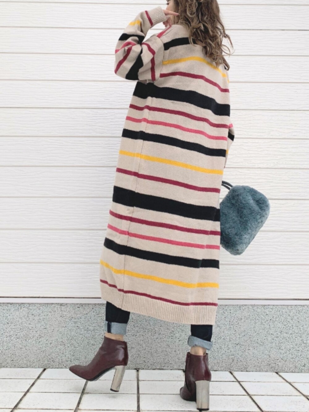ブルー系のデニムパンツ、ブラウン系のブーツ、ブルー系のトートバッグを着用したレディースの秋コーディネートの3枚目の写真
