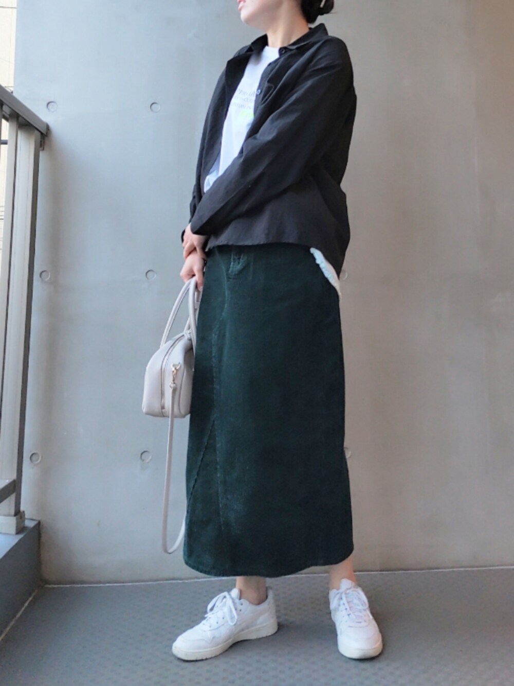 グリーン系のスカート、ホワイト系のスニーカー、ホワイト系のTシャツ/カットソーを着用したレディースの冬コーディネートの2枚目の写真