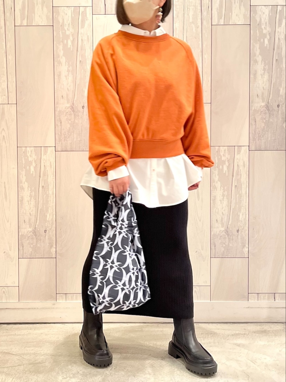 ブラック系のスカート、オレンジ系のスウェット、ホワイト系のシャツ/ブラウスを着用したレディースの秋コーディネートの2枚目の写真