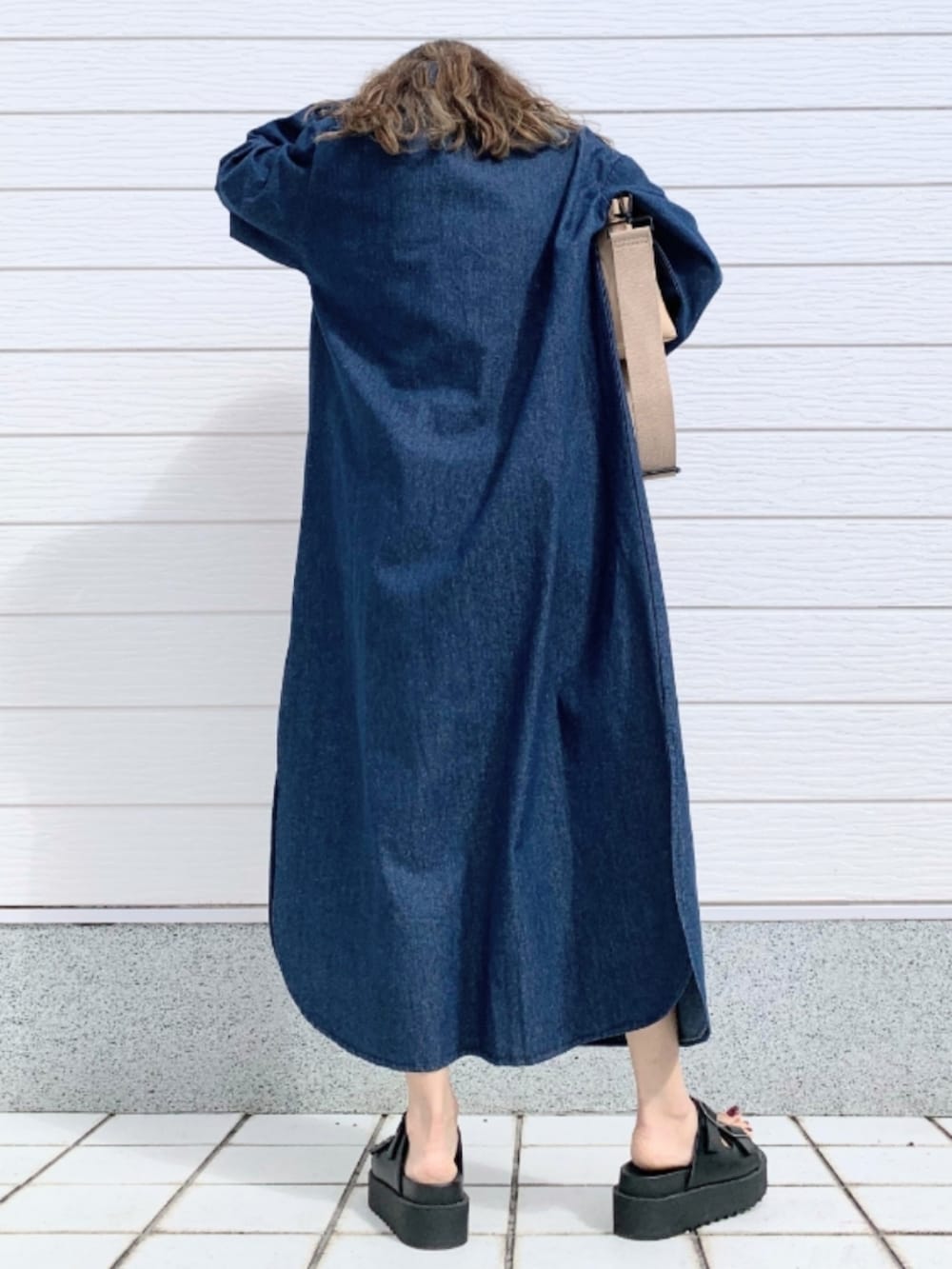 ブラック系のサンダル、ブルー系のシャツワンピース、ベージュ系のクラッチバッグを着用したレディースの春コーディネートの3枚目の写真