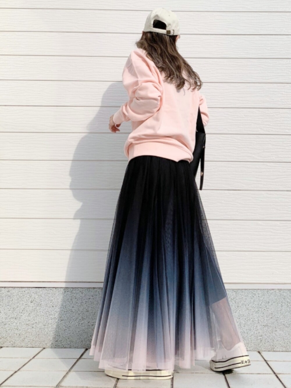 ブラック系のスカート、ホワイト系のスニーカー、ピンク系のスウェットを着用したレディースの春コーディネートの2枚目の写真