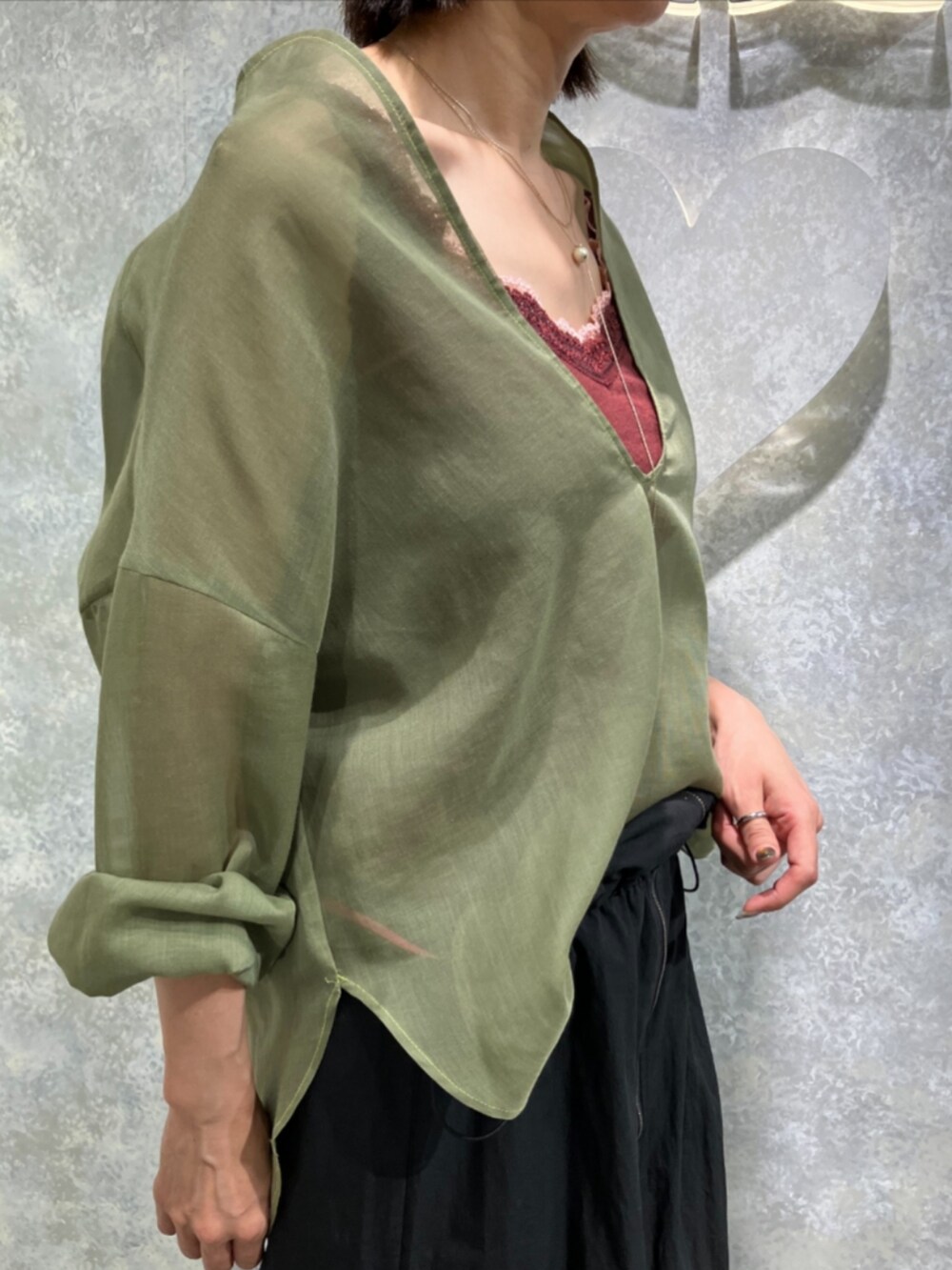 ブラック系のジャンパースカート、グリーン系のシャツ/ブラウス、レッド系のタンクトップを着用したレディースの秋コーディネートの4枚目の写真