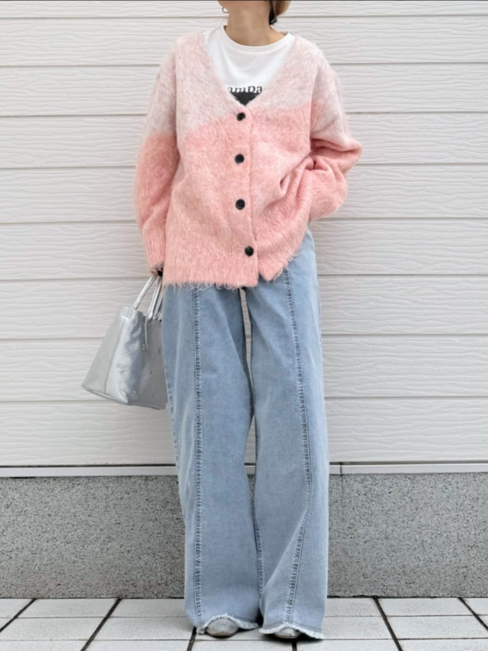 シルバー系のトートバッグ、ホワイト系のTシャツ/カットソー、ブルー系のデニムパンツを着用したレディースの冬コーディネートの2枚目の写真