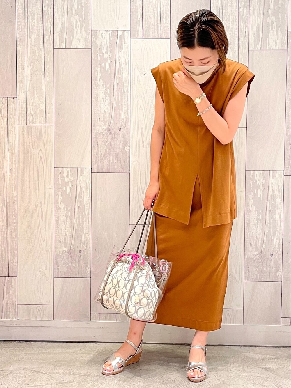 ピンク系のトートバッグ、ブラウン系のワンピース、ゴールド系のネックレスを着用したレディースの夏コーディネートの2枚目の写真