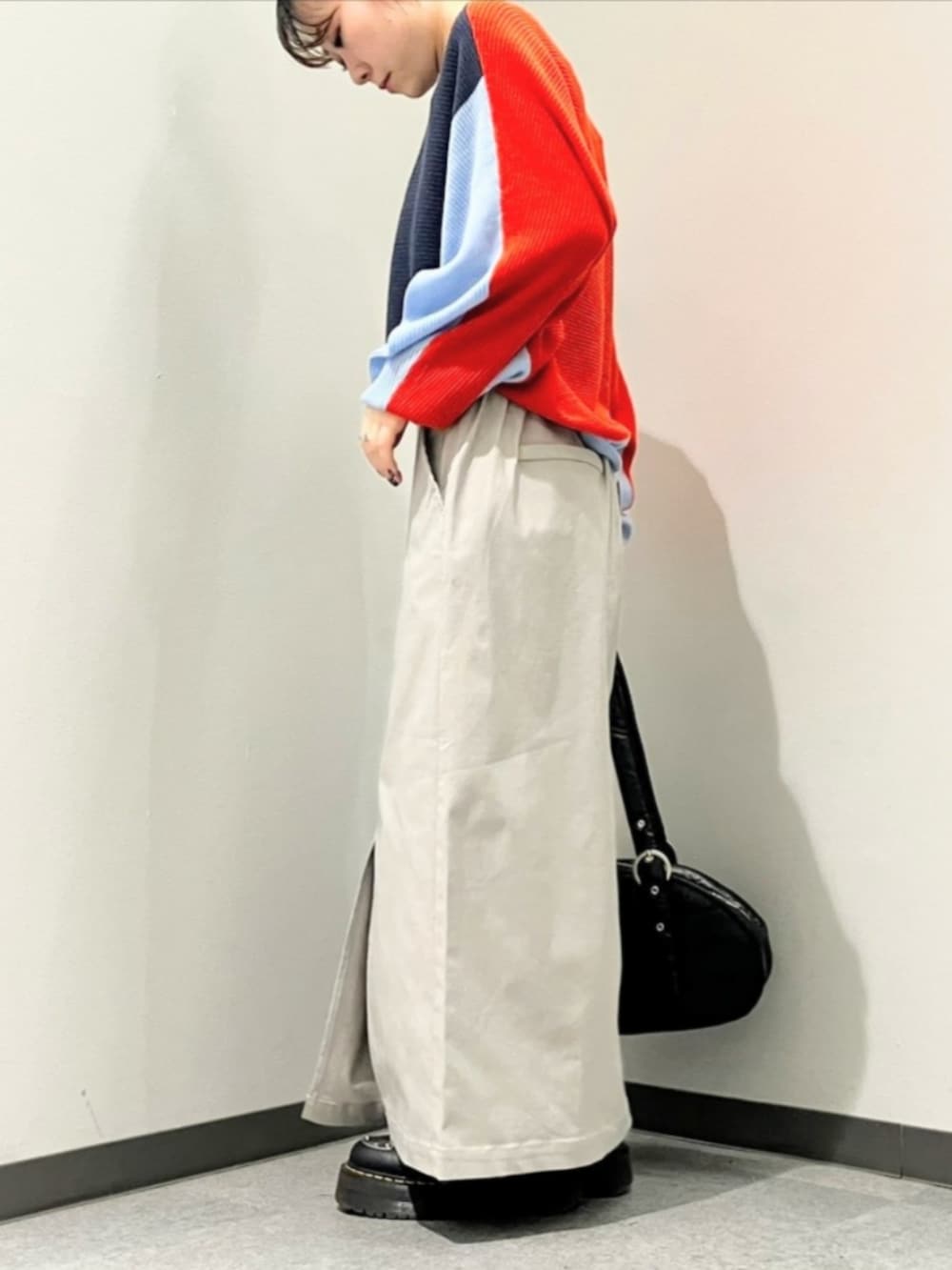 オレンジ系のニット/セーター、グレー系のスカート、ブラック系のボストンバッグを着用したレディースの秋コーディネートの3枚目の写真