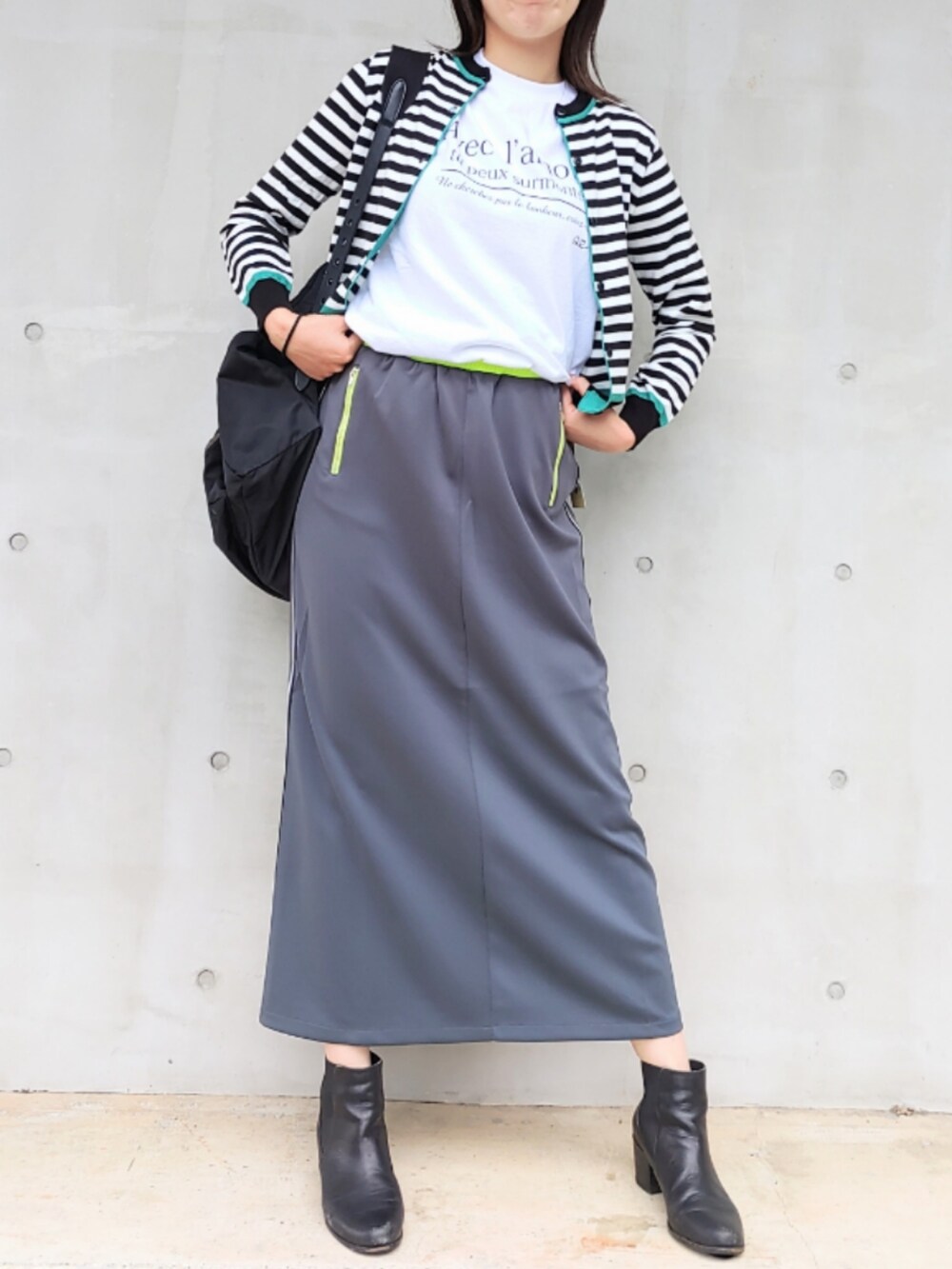 グレー系のスカート、ブラック系のカーディガン/ボレロ、ホワイト系のTシャツ/カットソーを着用したレディースの秋コーディネートの2枚目の写真