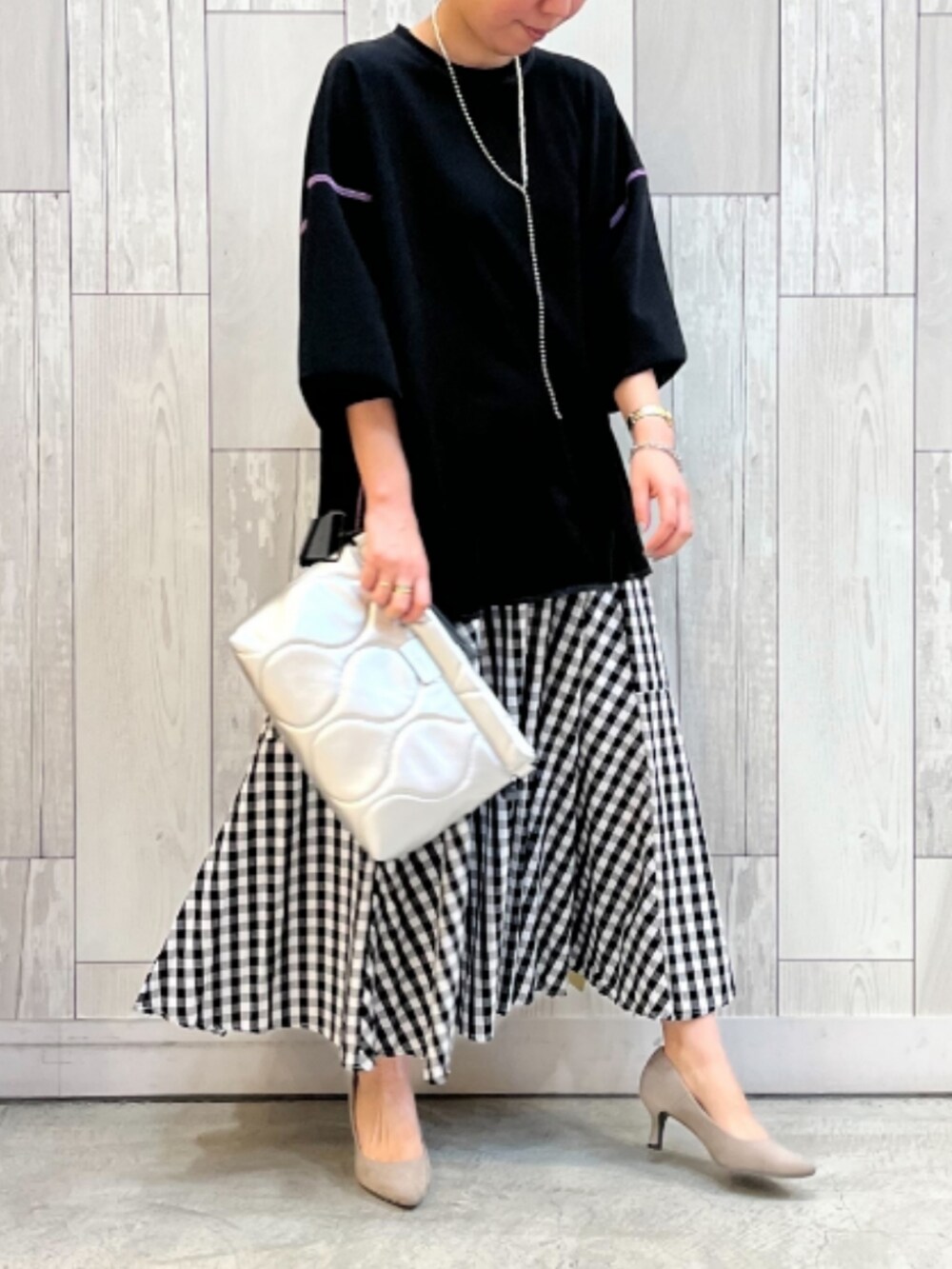 ブラック系のスカート、シルバー系のクラッチバッグ、ブラック系のTシャツ/カットソーを着用したレディースの春コーディネートの2枚目の写真
