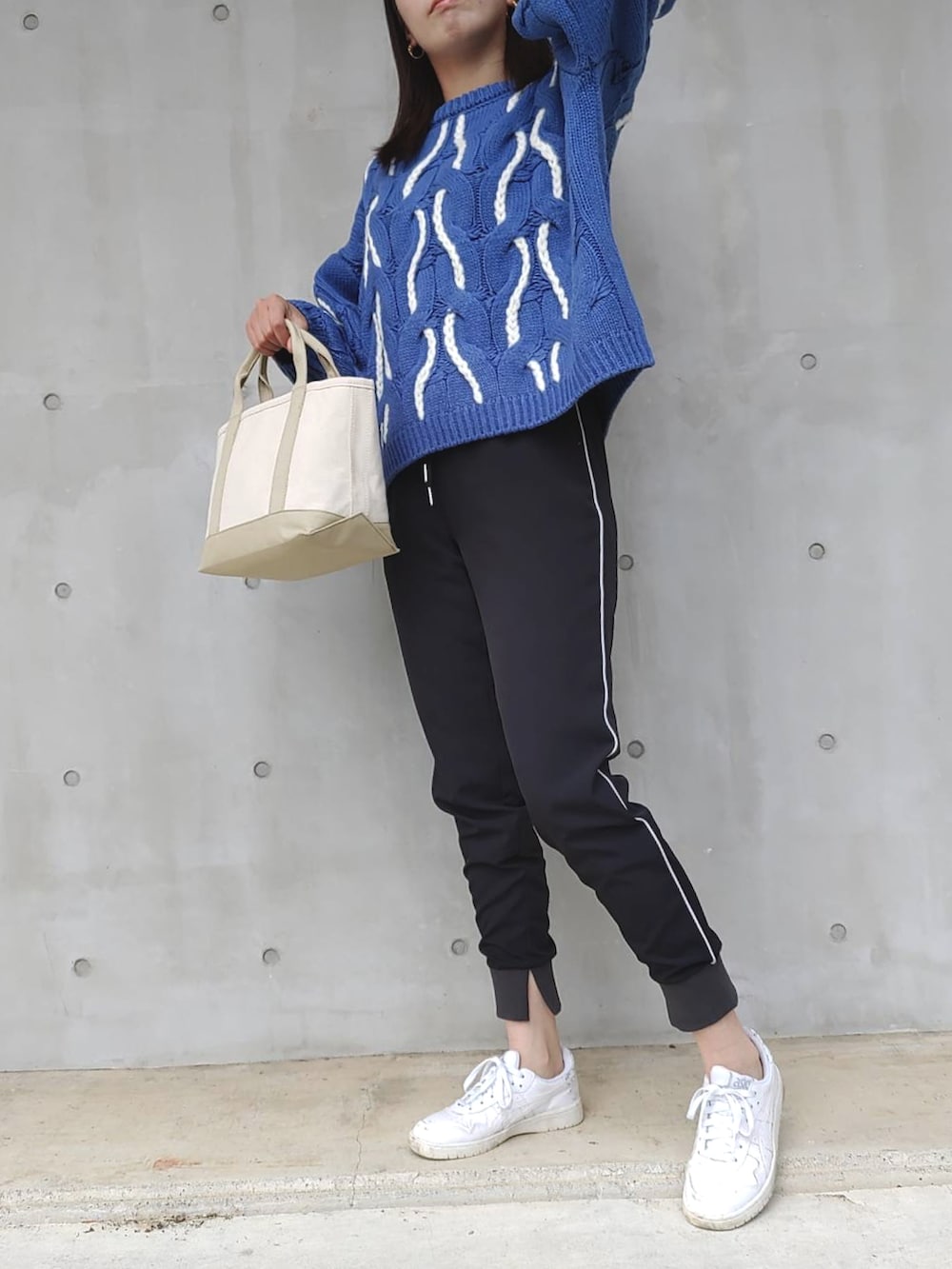ブラック系のその他パンツ、ブルー系のニット/セーター、ベージュ系のトートバッグを着用したレディースの秋コーディネートの3枚目の写真