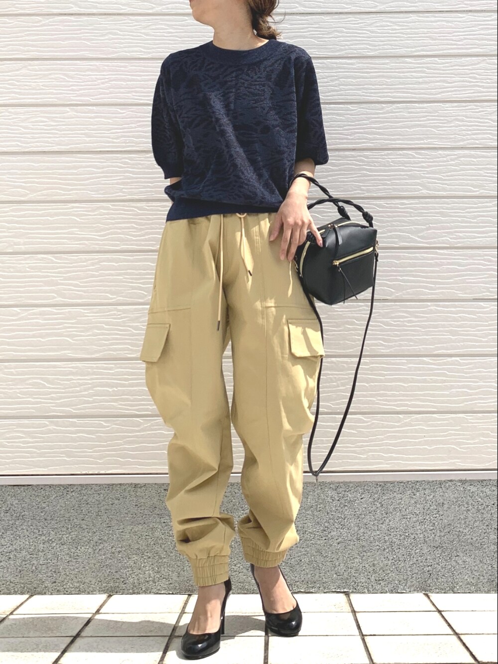 ブラック系のハンドバッグ、ブルー系のニット/セーター、ベージュ系のその他パンツを着用したレディースの春コーディネートの2枚目の写真