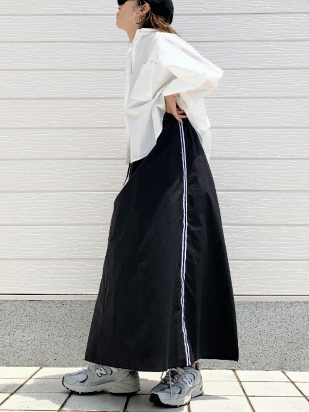 シルバー系のスニーカー、ホワイト系のシャツ/ブラウス、ブラック系のショルダーバッグを着用したレディースの夏コーディネートの2枚目の写真