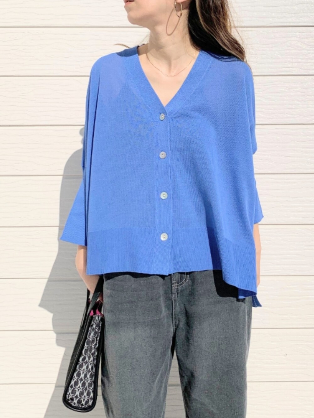 グレー系のデニムパンツ、ブラック系のショルダーバッグ、ブルー系のカーディガン/ボレロを着用したレディースの春コーディネートの4枚目の写真