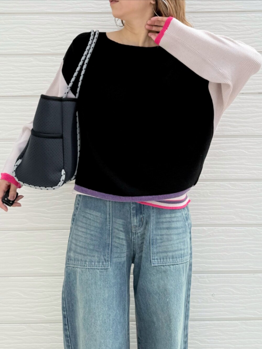 ブルー系のデニムパンツ、ブラック系のニット/セーター、ブルー系のトートバッグを着用したレディースの秋コーディネートの4枚目の写真