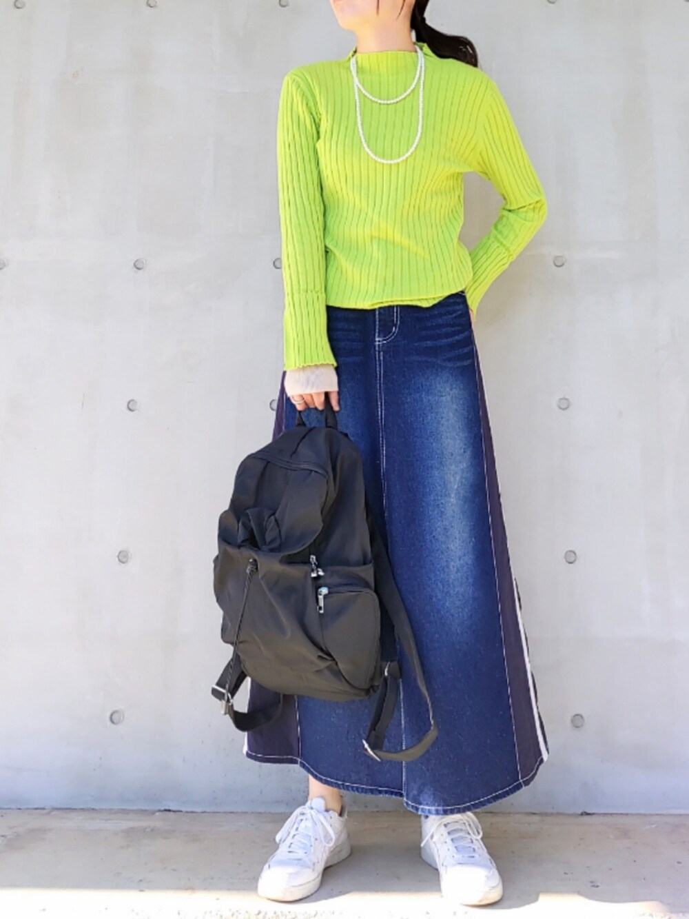 ブルー系のデニムスカート、グリーン系のニット/セーター、ブラック系のバックパック/リュックを着用したレディースの冬コーディネートの2枚目の写真