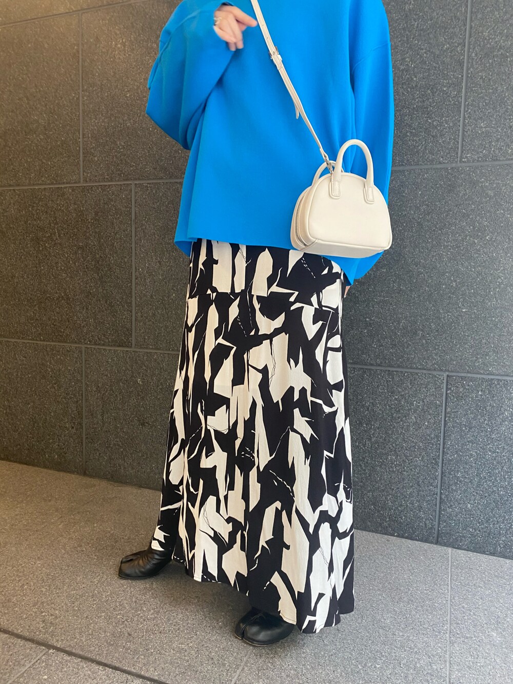 ブラック系のワンピース、ブラック系のブーツ、ホワイト系のショルダーバッグを着用したレディースの春コーディネートの3枚目の写真