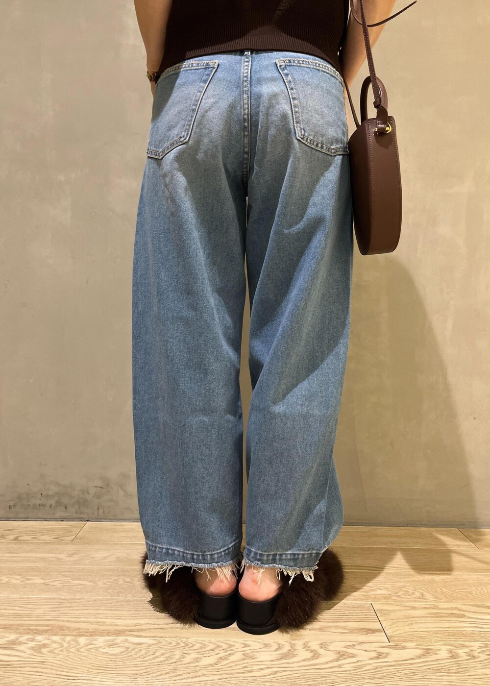 ブルー系のデニムパンツ、ブラウン系のサンダル、ブラウン系のベストを着用したレディースの夏コーディネートの7枚目の写真