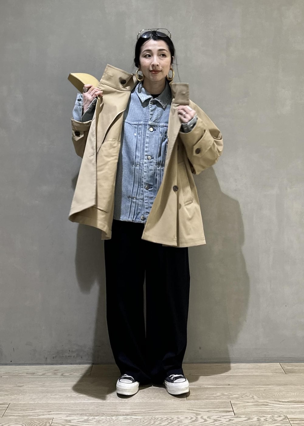 ベージュ系のトレンチコート、ブラック系のスラックス、イエロー系のキーホルダーを着用したレディースの冬コーディネートの3枚目の写真