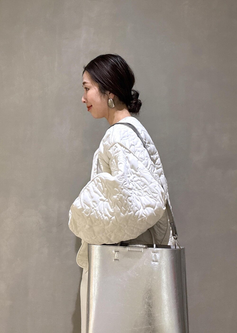 ホワイト系のパンプス、シルバー系のトートバッグ、ホワイト系のデニムパンツを着用したレディースの冬コーディネートの10枚目の写真