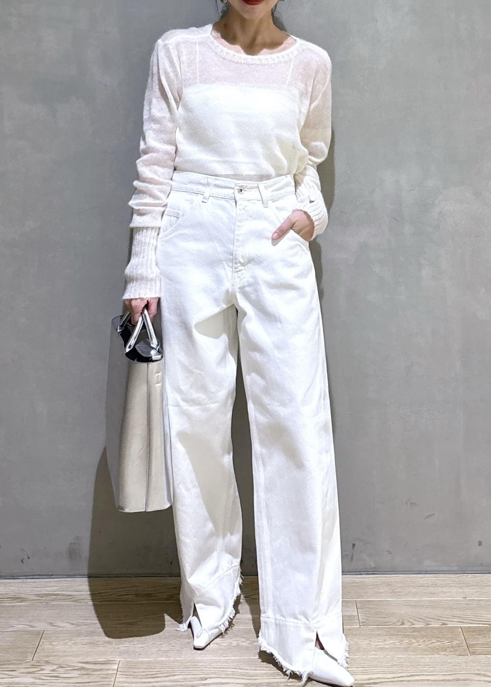 ホワイト系のパンプス、シルバー系のトートバッグ、ホワイト系のデニムパンツを着用したレディースの冬コーディネートの6枚目の写真