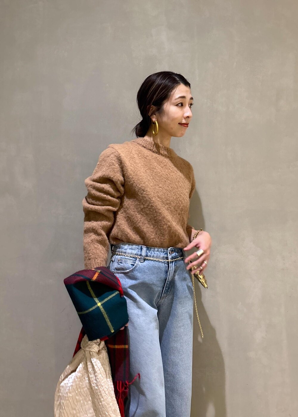 ホワイト系のハンドバッグ、ゴールド系のショルダーバッグ、ブルー系のデニムパンツを着用したレディースの冬コーディネートの8枚目の写真