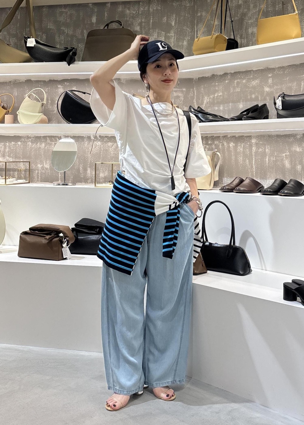ブルー系のデニムパンツ、ブラック系のショルダーバッグ、ブルー系のTシャツ/カットソーを着用したレディースの春コーディネートの4枚目の写真