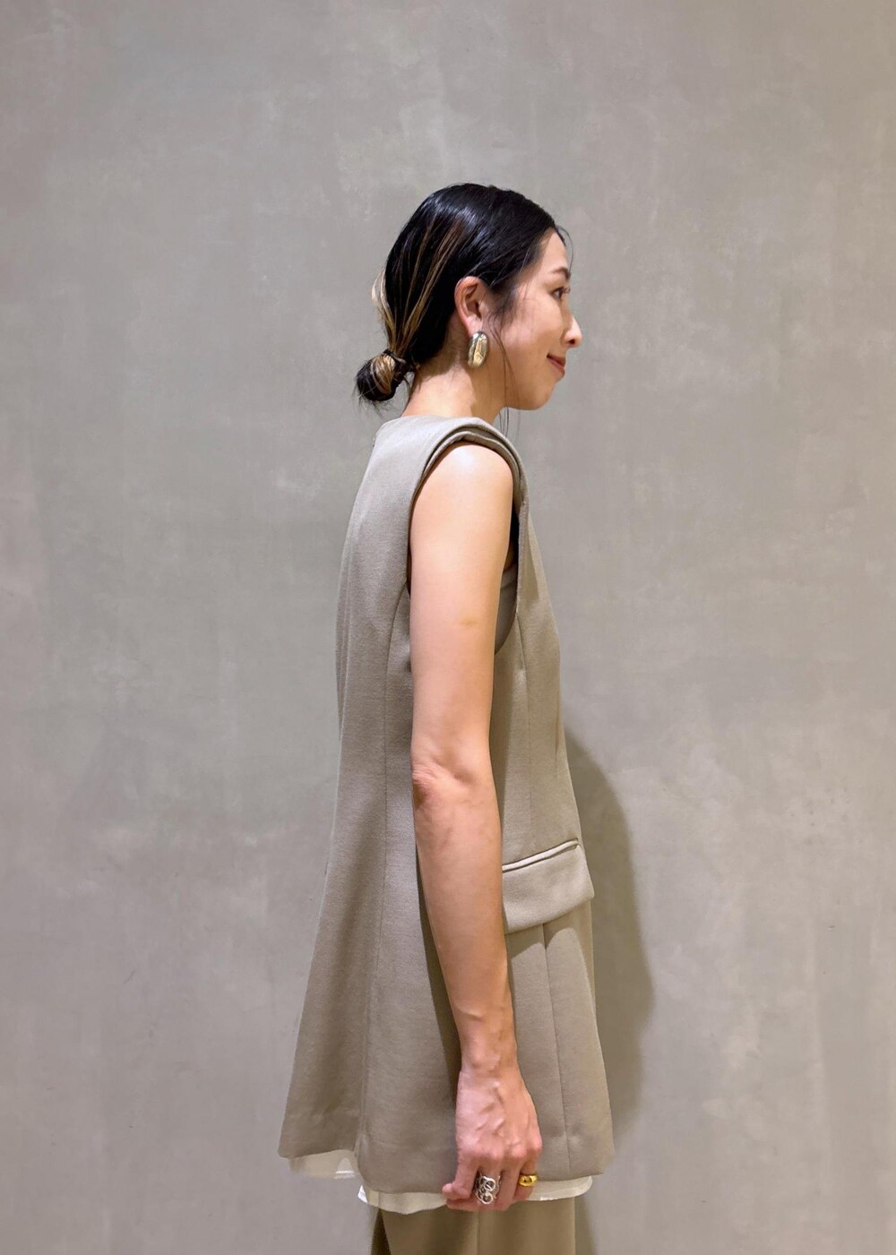 ブラック系のパンプス、ベージュ系のベスト、ベージュ系のスラックスを着用したレディースの夏コーディネートの9枚目の写真