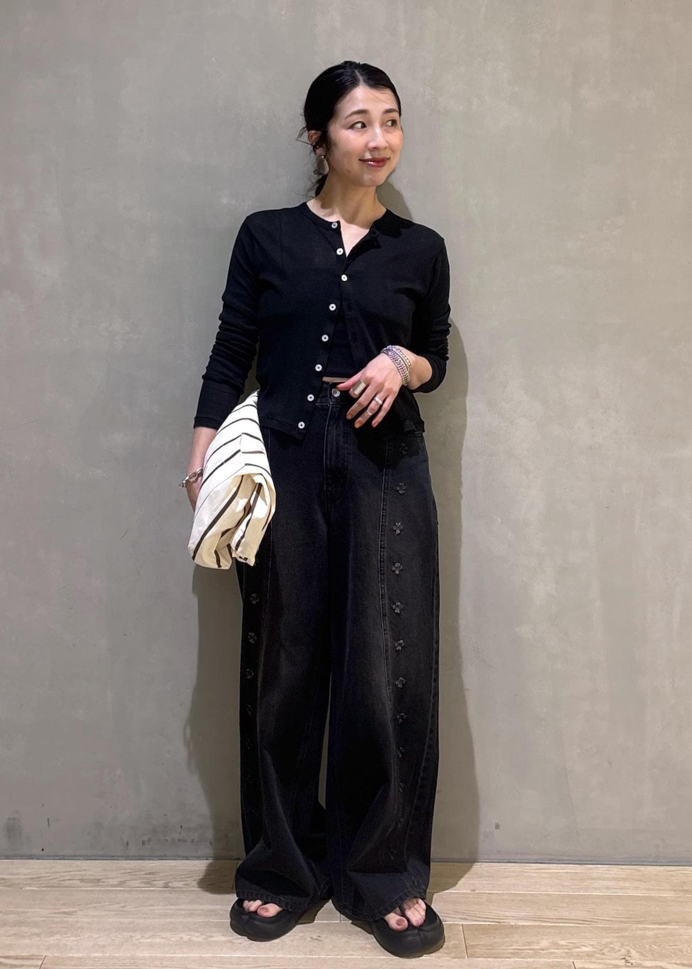 ブラック系のカーディガン/ボレロ、ホワイト系のショルダーバッグ、ブラック系のデニムパンツを着用したレディースの春コーディネートの6枚目の写真