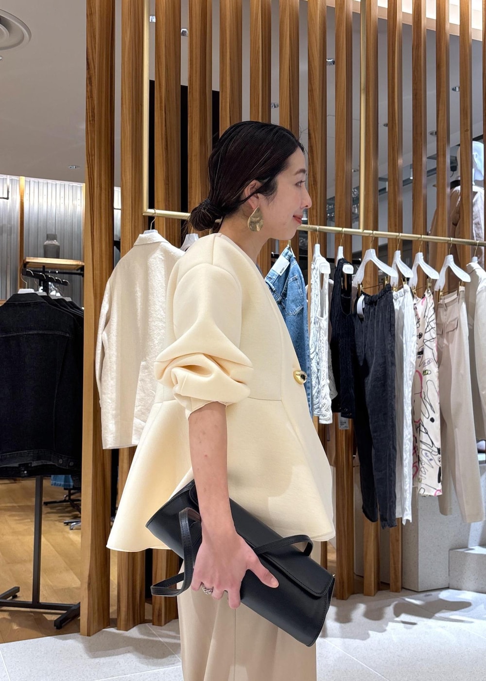 ブラック系のショルダーバッグ、ホワイト系のパンプス、ベージュ系のスラックスを着用したレディースの冬コーディネートの7枚目の写真