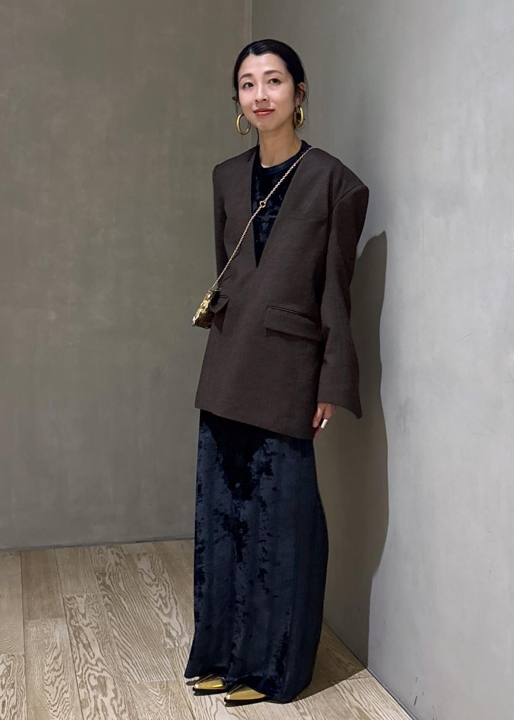 ブラック系のスカート、ブラック系のTシャツ/カットソー、ゴールド系のブーツを着用したレディースの冬コーディネートの2枚目の写真