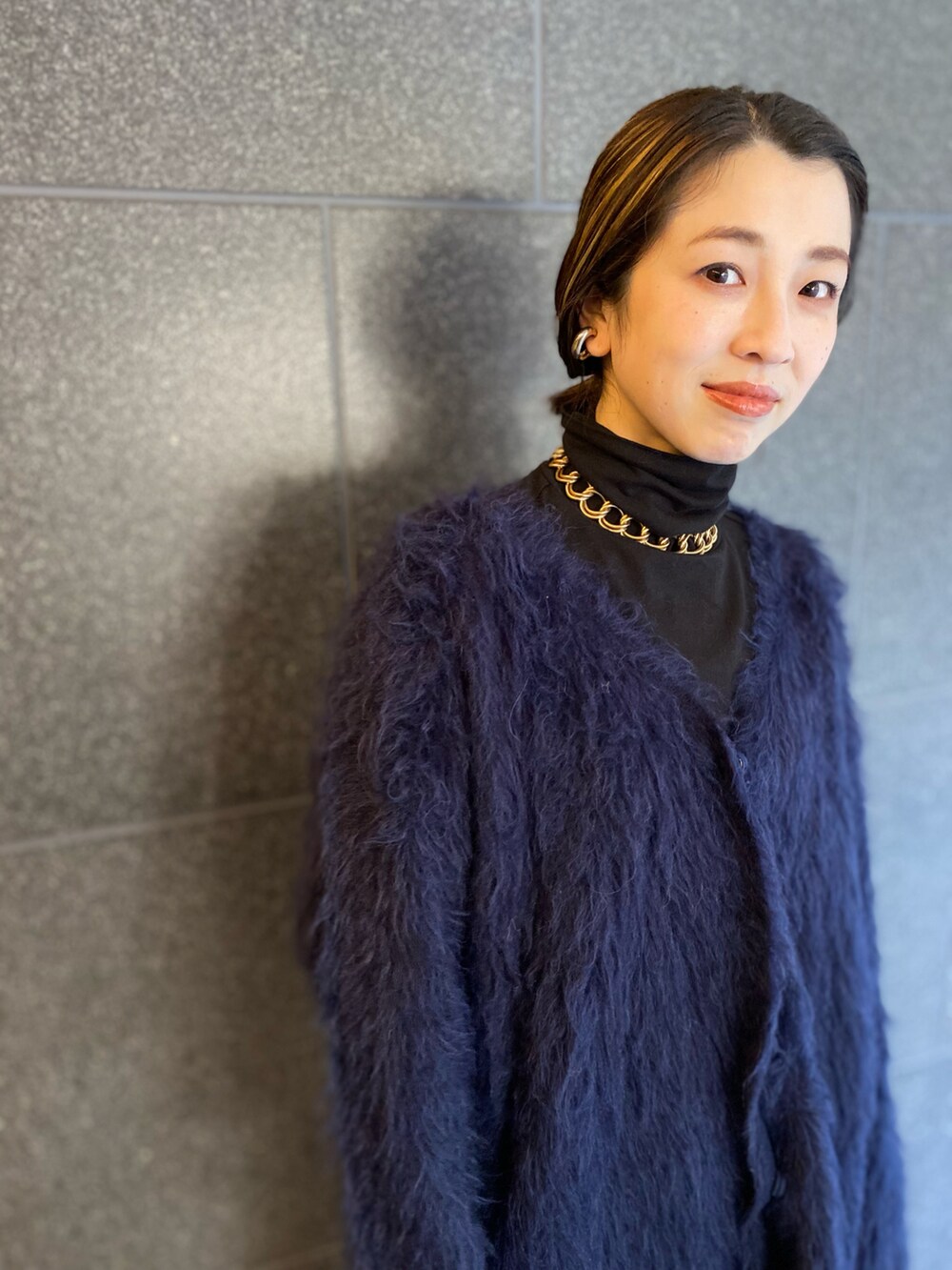 ブルー系のカーディガン/ボレロ、ブラック系のスカート、ゴールド系のバッグを着用したレディースの春コーディネートの2枚目の写真