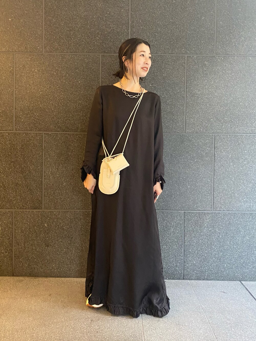 ホワイト系のショルダーバッグ、ブラック系のワンピース、シルバー系のネックレスを着用したレディースの春コーディネートの2枚目の写真