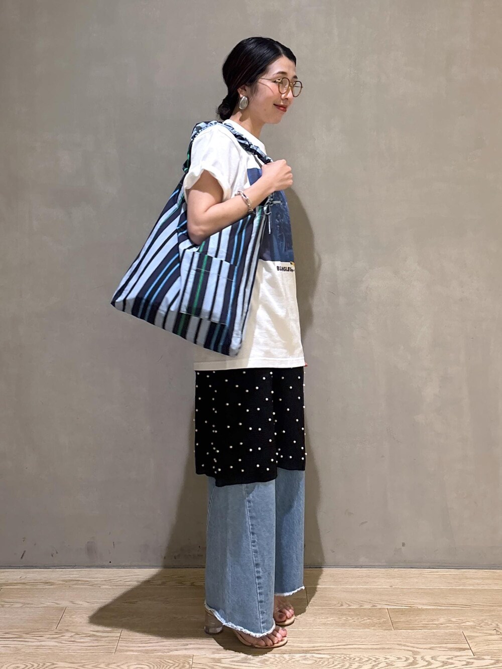 ブルー系のデニムパンツ、ブルー系のショルダーバッグ、ホワイト系のTシャツ/カットソーを着用したレディースの春コーディネートの4枚目の写真