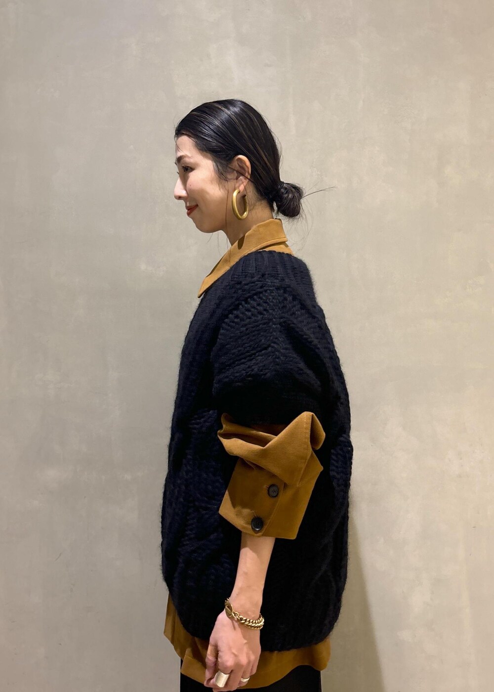 ブラック系のニット/セーター、ゴールド系のブーツ、イエロー系のブルゾンを着用したレディースの秋コーディネートの9枚目の写真