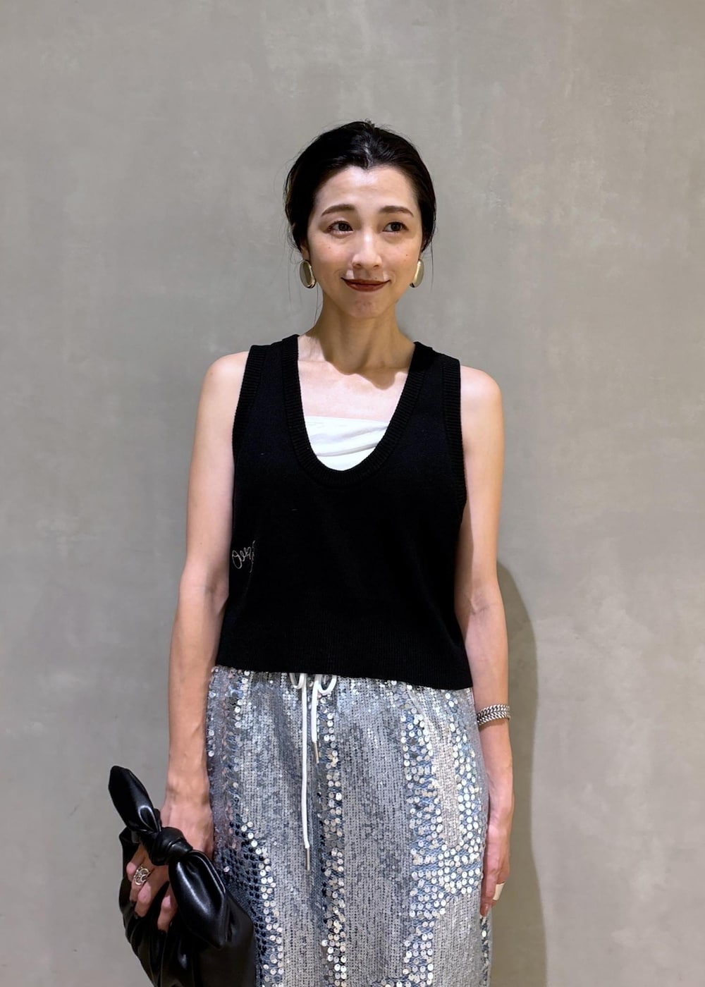 シルバー系のスカート、ブラック系のベスト、ブルー系のデニムパンツを着用したレディースの夏コーディネートの6枚目の写真