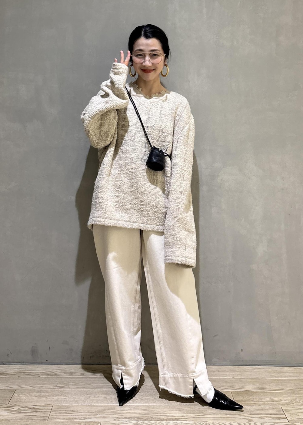 ブラック系のサンダル、ホワイト系のデニムパンツ、ブラック系のショルダーバッグを着用したレディースの冬コーディネートの2枚目の写真