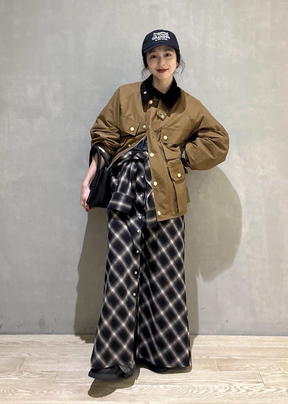 イエロー系のブルゾン、ブラック系のキャップを着用したレディースの秋コーディネートの2枚目の写真