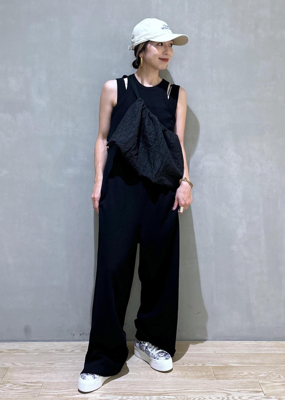 ブラック系のスニーカー、ブラック系のつなぎ/オールインワン、ベージュ系のキャップを着用したレディースの夏コーディネートの2枚目の写真