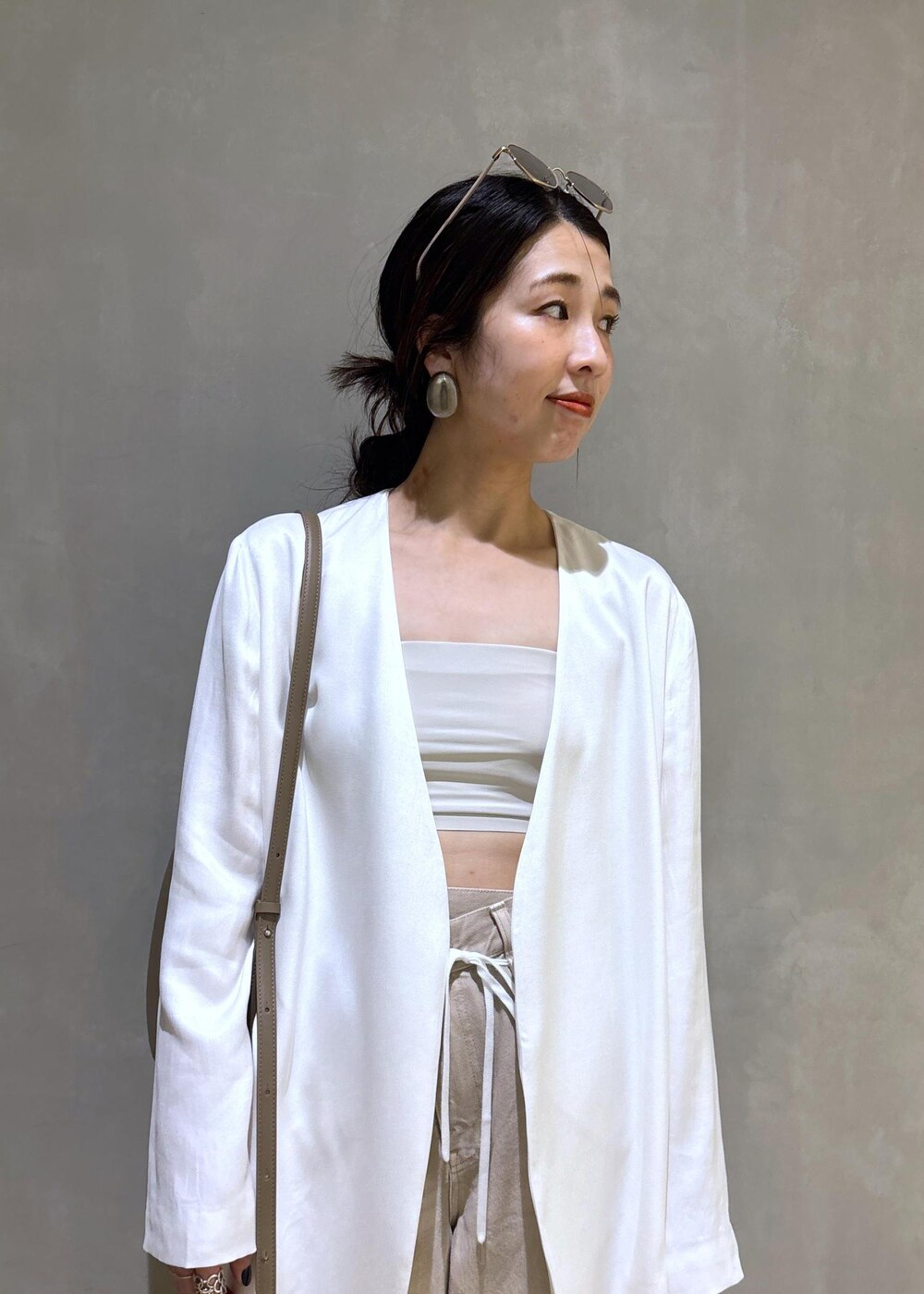 ホワイト系のノーカラージャケット、ホワイト系のデニムパンツ、グレー系のショルダーバッグを着用したレディースの春コーディネートの6枚目の写真